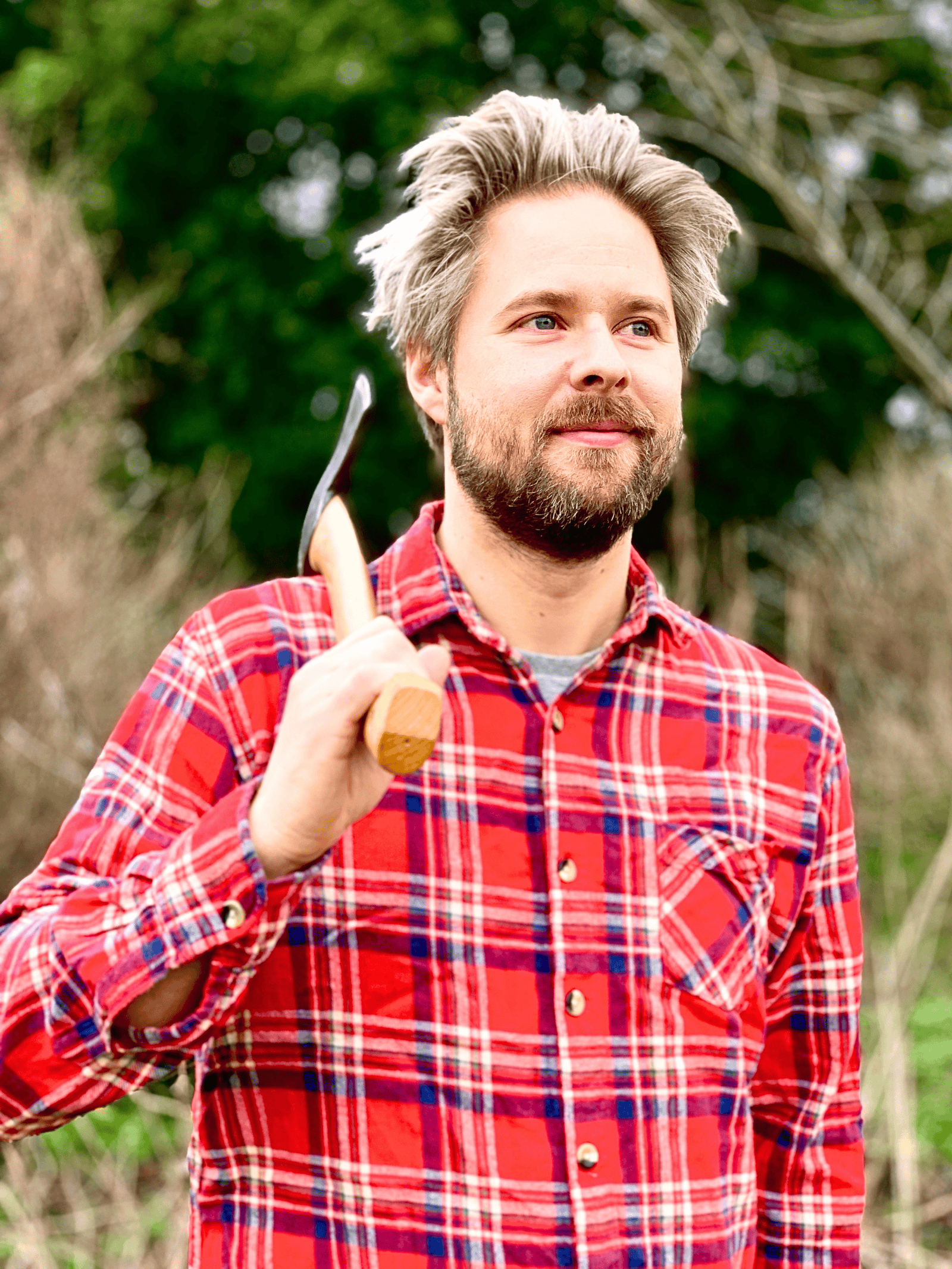 Woodworker Sebastian Ungh holding axe outdoors in a natural setting.