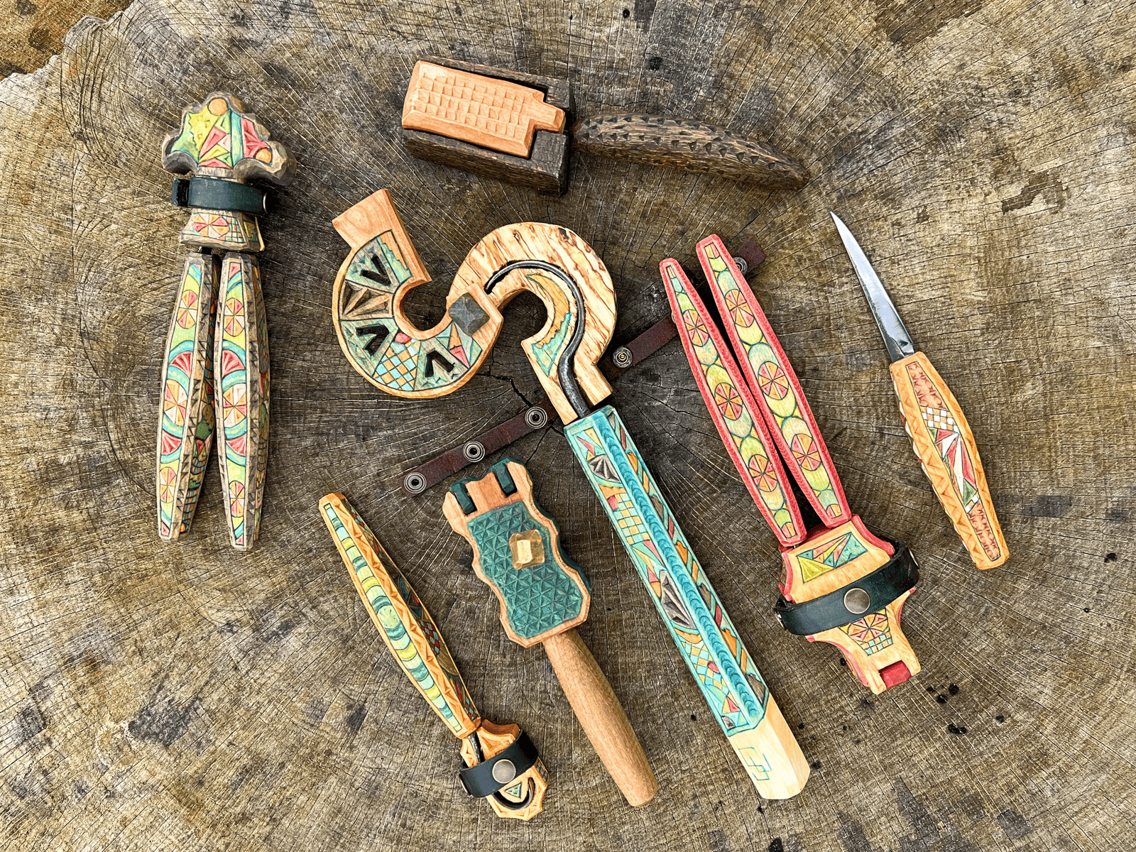 Handcrafted wooden tools with colorful tribal patterns on a rustic wooden surface.